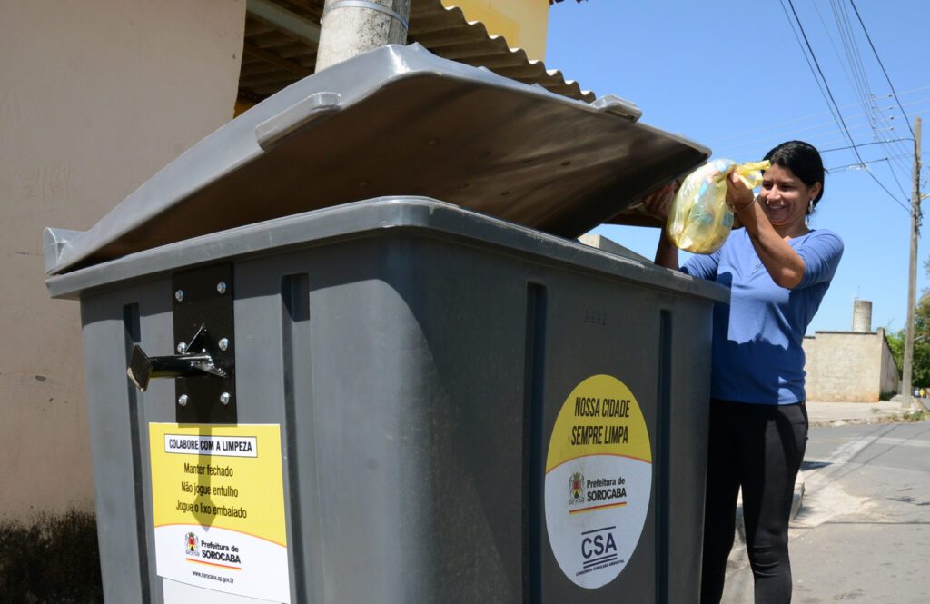 Mulher jogando o lixo em um contentor de lixo.